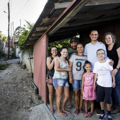 PORTO ALEGRE, RS, BRASIL, 26-12-2018: O gerente de recepção do hotel Sheraton, Eduardo Finamor, a mulher dele, Daniela Finamor (D), o filho do casal, Arthur Finamor, a cunhada Débora dos Santos (E), a irmã Eliane Finamor, o pai João Finamor, Mara Finamor e Rafaella Lopes, no beco de chão batido em frente à casa onde Eduardo viveu com a família, na Vila Pinto, no bairro Bom Jesus. Finamor começou a trabalhar no hotel graças a uma ONG que acenou com a possibilidade. Ele foi repositor de frigobar, mensageiro e porteiro, entre outras atividades, até ser promovido a gerente neste ano. (Foto: Mateus Bruxel / Agência RBS)