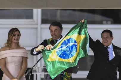  Brazils new President Jair Bolsonaro (C) and Brazils new Vice-President Hamilton Mourao (R), display a Brazilian national flag next to First Lady Michelle Bolsonaro, during their inauguration ceremony at Planalto Palace in Brasilia on January 1, 2019. - Bolsonaro takes office with promises to radically change the path taken by Latin Americas biggest country by trashing decades of centre-left policies. (Photo by EVARISTO SA / various sources / AFP)Editoria: POLLocal: BrasíliaIndexador: EVARISTO SASecao: governmentFonte: EVARISTO SAFotógrafo: STF