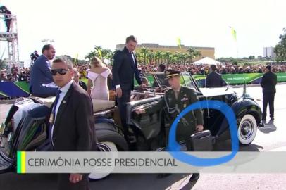 Reprodução de imagem da TV Globo mostra ajudante-de-ordens da Presidência segurando maleta ao lado do carro aberto que levava o presidente Jair Bolsonaro e a primeira-dama.