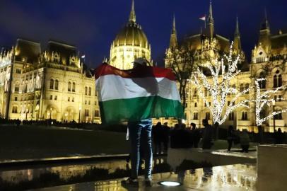 A protester holds up a Hungarian flag at the parliament building during a demonstration organised by trade unions, political parties and civil organisations to protest against the dubbed slave law on January 5, 2019. - The law, that was voted by Hungarian Parliament on December 12, 2018 and then signed by the President, hikes the amount of overtime that employers can demand from 250 to 400 hours per year and allows payment to be delayed by up to three years. (Photo by FERENC ISZA / AFP)