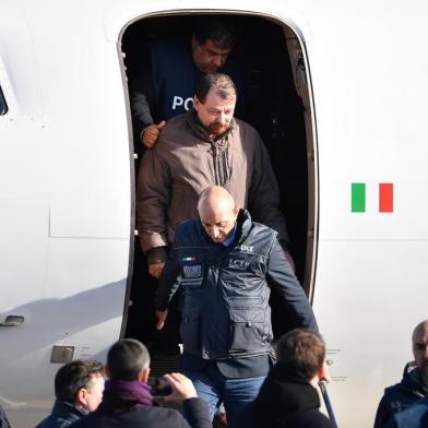  Italian former communist militant Cesare Battisti (Top C), wanted in Rome for four murders attributed to a far-left group in the 1970s, is escorted by Italian Police officers as he steps off a plane coming from Bolivia and chartered by Italian authorities, after landing at Ciampino airport in Rome on January 14, 2019. - Former communist militant Cesare Battisti landed in Rome on January 14 after an international police squad tracked the Italian down and arrested him in Bolivia, ending almost four decades on the run. (Photo by Alberto PIZZOLI / AFP)Editoria: POLLocal: RomeIndexador: ALBERTO PIZZOLISecao: politics (general)Fonte: AFPFotógrafo: STF