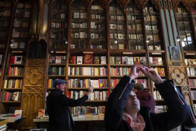 Tourists take pictures inside the Lello bookshop, a Gothic Revival style bookstore in the historic centre of Porto, on January 12, 2019. - On the brink of bankruptcy, the historic Lello Bookstore, which allegedly inspired J.K Rowling to write Harry Potter, has started charging an entrance fee to tourists. (Photo by MIGUEL RIOPA / AFP)