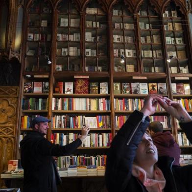 Tourists take pictures inside the Lello bookshop, a Gothic Revival style bookstore in the historic centre of Porto, on January 12, 2019. - On the brink of bankruptcy, the historic Lello Bookstore, which allegedly inspired J.K Rowling to write Harry Potter, has started charging an entrance fee to tourists. (Photo by MIGUEL RIOPA / AFP)