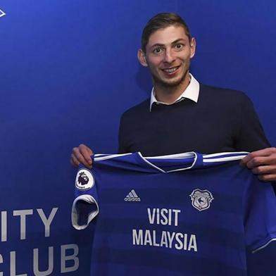  Picture released by Cardiff City FC via Noticias Argentinas, showing Argentine footballer Emiliano Sala posing with Cardiffs jersey after signing for the club, in Cardiff, on January 20, 2019. - Premier League club Cardiff Citys record new signing, Argentine striker Emiliano Sala, is missing presumed dead after a light aircraft he was travelling in disappeared over the English Channel on January 21, 2019. Police on the British island of Guernsey have suspended their search for the evening on January 22. Sala was heading to the Welsh capital after saying his final goodbyes to former teammates at French Ligue 1 Nantes. (Photo by HO / NOTICIAS ARGENTINAS / AFP) / - Argentina OUT / RESTRICTED TO EDITORIAL USE - MANDATORY CREDIT AFP PHOTO / CCFC / NA - NO MARKETING NO ADVERTISING CAMPAIGNS - DISTRIBUTED AS A SERVICE TO CLIENTSEditoria: SPOLocal: CardiffIndexador: HOSecao: soccerFonte: NOTICIAS ARGENTINASFotógrafo: STR