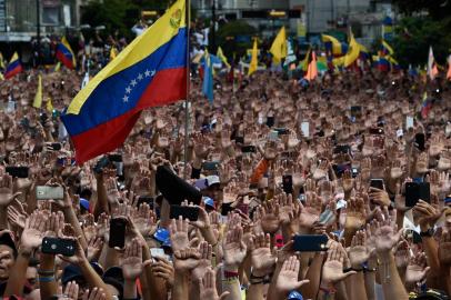  People raise their hands during a mass opposition rally against President Nicolas Maduro in which Venezuelas National Assembly head Juan Guaido (out of frame) declared himself the countrys acting president, on the anniversary of a 1958 uprising that overthrew a military dictatorship, in Caracas on January 23, 2019. - I swear to formally assume the national executive powers as acting president of Venezuela to end the usurpation, (install) a transitional government and hold free elections, said Guaido as thousands of supporters cheered. Moments earlier, the loyalist-dominated Supreme Court ordered a criminal investigation of the opposition-controlled legislature. (Photo by Federico PARRA / AFP)Editoria: WARLocal: CaracasIndexador: FEDERICO PARRASecao: crisisFonte: AFPFotógrafo: STF