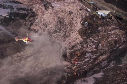  A firefighters helicopter overflies the area as rescuers work in the search for victims after the collapse of a dam, which belonged to Brazils giant mining company Vale, near the town of Brumadinho in southeastern Brazil, on January 25, 2019. - A dam collapse in southeast Brazil unleashed a torrent of mud on a riverside town and surrounding farmland Friday, destroying houses, leaving 200 people missing and raising fears of a number of deaths, according to officials. (Photo by Douglas Magno / AFP)Editoria: DISLocal: BrumadinhoIndexador: DOUGLAS MAGNOSecao: accident (general)Fonte: AFPFotógrafo: STR