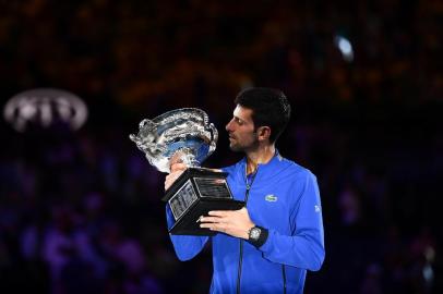 Serbias Novak Djokovic celebrates with the championship trophy during the presentation ceremony after his victory against Spains Rafael Nadal in the mens singles final on day 14 of the Australian Open tennis tournament in Melbourne on January 27, 2019. (Photo by Saeed KHAN / AFP) / -- IMAGE RESTRICTED TO EDITORIAL USE - STRICTLY NO COMMERCIAL USE --