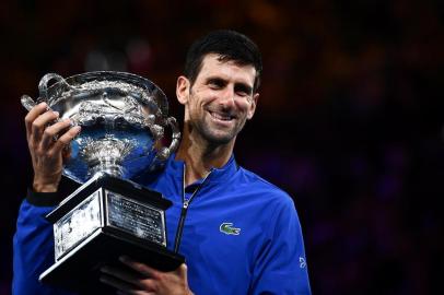  Serbias Novak Djokovic celebrates with the championship trophy during the presentation ceremony after his victory against Spains Rafael Nadal in the mens singles final on day 14 of the Australian Open tennis tournament in Melbourne on January 27, 2019. (Photo by Saeed KHAN / AFP) / -- IMAGE RESTRICTED TO EDITORIAL USE - STRICTLY NO COMMERCIAL USE --Editoria: SPOLocal: MelbourneIndexador: SAEED KHANSecao: tennisFonte: AFPFotógrafo: STF