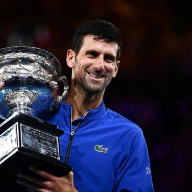  Serbias Novak Djokovic celebrates with the championship trophy during the presentation ceremony after his victory against Spains Rafael Nadal in the mens singles final on day 14 of the Australian Open tennis tournament in Melbourne on January 27, 2019. (Photo by Saeed KHAN / AFP) / -- IMAGE RESTRICTED TO EDITORIAL USE - STRICTLY NO COMMERCIAL USE --Editoria: SPOLocal: MelbourneIndexador: SAEED KHANSecao: tennisFonte: AFPFotógrafo: STF