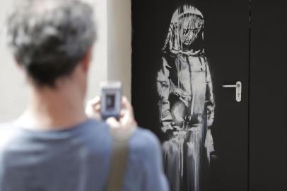 (FILES) In this file photo taken on June 25, 2018, a man takes a photograph of an artwork by street artist Banksy in Paris on a side street to the Bataclan concert hall where a terrorist attack killed 90 people on Novembre 13, 2015. - The artwork by street artist Banksy on a side street to the Bataclan concert hall was stolen in Paris on January 26, 2019. (Photo by Thomas SAMSON / AFP) / RESTRICTED TO EDITORIAL USE - MANDATORY MENTION OF THE ARTIST UPON PUBLICATION - TO ILLUSTRATE THE EVENT AS SPECIFIED IN THE CAPTION