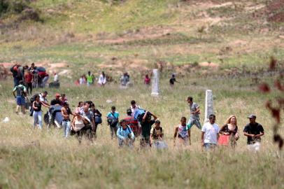 People walk through a field as they try to cross the border between Venezuela and Brazil in PacaraimaPeople walk through a field as they try to cross the border between Venezuela and Brazil in Pacaraima, Roraima state, Brazil, February 22, 2019. REUTERS/Ricardo Moraes ORG XMIT: BRA034Local: PACARAIMA ;Brazil