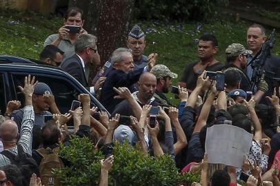 Brazilian former president (2003-2011) Luiz Inacio Lula da Silva  (C-waving) is escorted by security forces upon arrival at Jardim da Colina cemetery, in Sao Bernardo do Campo, Sao Paulo, Brazil after leaving the Federal Police headquarters in Curitiba, Parana state, where he is serving a 12-year prison sentence, to attend the funeral of his grandson on March 2, 2019. - Brazils jailed former president Luiz Inacio Lula da Silva on Friday was granted leave from prison to attend the weekend funeral of his young grandson, who died at the age of seven. (Photo by Miguel SCHINCARIOL / AFP)