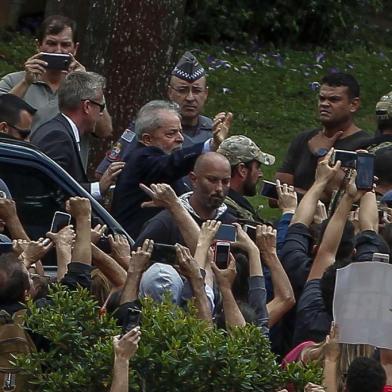 Brazilian former president (2003-2011) Luiz Inacio Lula da Silva  (C-waving) is escorted by security forces upon arrival at Jardim da Colina cemetery, in Sao Bernardo do Campo, Sao Paulo, Brazil after leaving the Federal Police headquarters in Curitiba, Parana state, where he is serving a 12-year prison sentence, to attend the funeral of his grandson on March 2, 2019. - Brazil's jailed former president Luiz Inacio Lula da Silva on Friday was granted leave from prison to attend the weekend funeral of his young grandson, who died at the age of seven. (Photo by Miguel SCHINCARIOL / AFP)