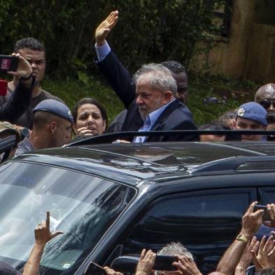 Brazilian former president (2003-2011) Luiz Inacio Lula da Silva (C) waves to supporters as he leaves the Jardim da Colina cemetery, in Sao Bernardo do Campo, Sao Paulo, Brazil where he attended his grandson's funeral on March 2, 2019, after a federal court authorised his release for a few hours from the Federal Police headquarters in Curitiba, Parana state, where he is serving a 12-year prison sentence. - Brazil's jailed former president Luiz Inacio Lula da Silva on Friday was granted leave from prison to attend the weekend funeral of his young grandson, who died at the age of seven. (Photo by Miguel SCHINCARIOL / AFP)