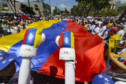 Supporters of Venezuelan opposition leader and self-proclaimed acting president Juan Guaido demonstrate with a giant Venezuelan national flag as they wait for his return in Caracas on March 4, 2019. - Opposition supporters in Venezuela were set to take to the streets Monday after leader Juan Guaido called for mass protests against President Nicolas Maduro -- as the self-declared interim president prepared to return after a week touring Latin American allies. (Photo by Matias DELACROIX / AFP)