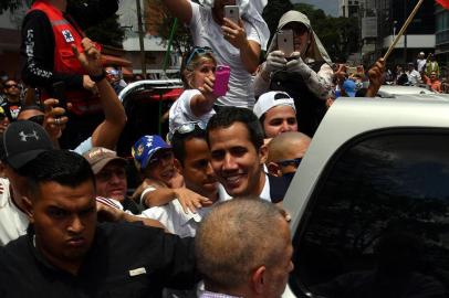 Venezuelan opposition leader and self-proclaimed acting president Juan Guaido (C) is surrounded by supporters upon his arrival in Caracas on March 4, 2019. - Venezuelas opposition leader Juan Guaido was mobbed by supporters, media and the ambassadors of allied countries as he returned to Caracas on Monday, defying the threat of arrest from embattled President Nicolas Maduros regime. Just before his arrival, US Vice President Mike Pence sent a warning to Maduro to ensure Guaidos safety. (Photo by Yuri CORTEZ / AFP)