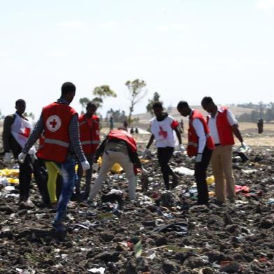 Red cross team work amid debris at the crash site of Ethiopia Airlines near Bishoftu, a town some 60 kilometres southeast of Addis Ababa, Ethiopia, on March 10, 2019. - An Ethiopian Airlines Boeing 737 crashed on March 10 morning en route from Addis Ababa to Nairobi with 149 passengers and eight crew believed to be on board, Ethiopian Airlines said. (Photo by Michael TEWELDE / AFP)