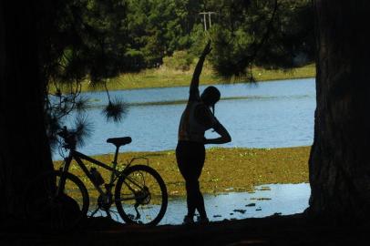  Exercício Físico. Jovens fazendo alongamento e ciclismo na beira da lagoa.