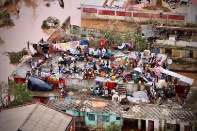 People gather on the roof of a house submerged by floods in Buzi on March 20, 2019. - International aid agencies raced on March 20 to rescue survivors and meet spiralling humanitarian needs in three impoverished countries battered by one of the worst storms to hit southern Africa in decades. Five days after tropical cyclone Idai cut a swathe through Mozambique, Zimbabwe and Malawi, the confirmed death toll stood at more than 300 and hundreds of thousands of lives were at risk, officials said. (Photo by ADRIEN BARBIER / AFP)