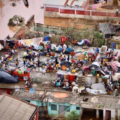 People gather on the roof of a house submerged by floods in Buzi on March 20, 2019. - International aid agencies raced on March 20 to rescue survivors and meet spiralling humanitarian needs in three impoverished countries battered by one of the worst storms to hit southern Africa in decades. Five days after tropical cyclone Idai cut a swathe through Mozambique, Zimbabwe and Malawi, the confirmed death toll stood at more than 300 and hundreds of thousands of lives were at risk, officials said. (Photo by ADRIEN BARBIER / AFP)