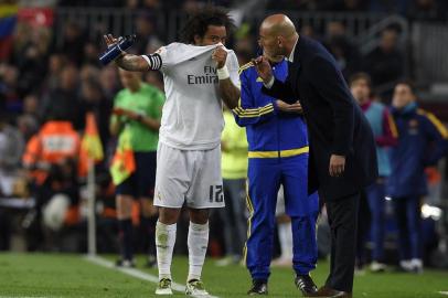 Real Madrids Brazilian defender Marcelo (L) talks with Real Madrids French coach Zinedine Zidane (R) during the Spanish league Clasico football match FC Barcelona vs Real Madrid CF at the Camp Nou stadium in Barcelona on April 2, 2016. / AFP / LLUIS GENE