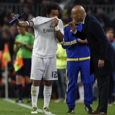 Real Madrids Brazilian defender Marcelo (L) talks with Real Madrids French coach Zinedine Zidane (R) during the Spanish league Clasico football match FC Barcelona vs Real Madrid CF at the Camp Nou stadium in Barcelona on April 2, 2016. / AFP / LLUIS GENE