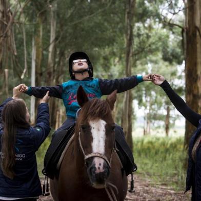 VACARIA, RS, BRASIL, 13-03-2019: RS que Inspira. A coordenadora da ONG Passo Amigo, Juliana Biazus da Silva (E), durante atendimento do menino Brayan Ostzyzek, no Parque dos Rodeios Nicanor Kramer da Luz, em Vacaria. A organização não tem fins lucrativos e oferece o serviço de equoterapia a pessoas com necessidades específicas, dificuldades escolares e problemas emocionais. (Foto: Mateus Bruxel / Agência RBS)