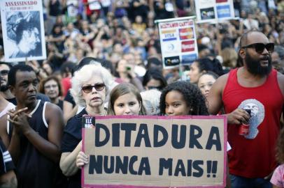 A girl holds a sign reading Dictatorship never again during a demonstration at Cinelandia square in Rio de Janeiro, Brazil on March 31, 2019, to protest against the commemoration of the 55th anniversary of the coup that established more than two decades of military rule. - Thousands of protesters took to the streets of Brazil for the 55th anniversary of the coup, the protests were sparked by the order recently issued by far-right President Jair Bolsonaro for defense forces to appropriately commemorate the overthrow of President Joao Goulart. (Photo by Daniel RAMALHO / AFP)