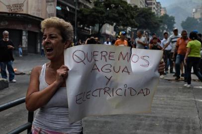 A woman holds a placard reading We Want Water and Electricity as she shouts slogans during a protest for the lack of water and electric service during a new power outage in Venezuela, at Fuerzas Armadas Avenue in Caracas on March 31, 2019. - Living conditions are plummeting in the oil-producing Latin American nation, which is spiralling ever deeper into economic chaos during a protracted political crisis. (Photo by Federico PARRA / AFP)