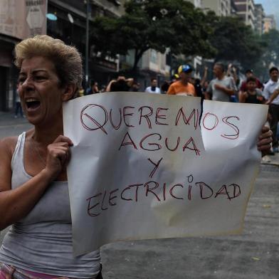 A woman holds a placard reading We Want Water and Electricity as she shouts slogans during a protest for the lack of water and electric service during a new power outage in Venezuela, at Fuerzas Armadas Avenue in Caracas on March 31, 2019. - Living conditions are plummeting in the oil-producing Latin American nation, which is spiralling ever deeper into economic chaos during a protracted political crisis. (Photo by Federico PARRA / AFP)