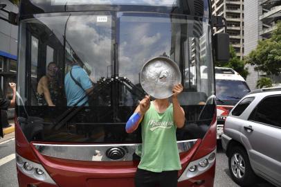 An opposition supporter stands in front of a bus as he demonstrates against the lack of water and electricity in Venezuela, in the neighbourhood of Los Palos Grandes in Caracas, on March 31, 2019. - Living conditions are plummeting in the oil-producing Latin American nation, which is spiralling ever deeper into economic chaos during a protracted political crisis. (Photo by Yuri CORTEZ / AFP)