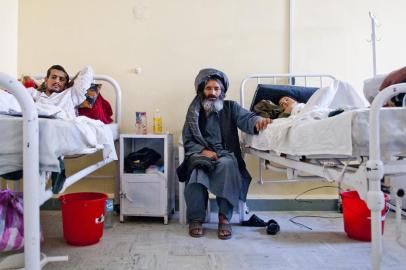 A father (middle) sits with his injured son in the male inpatient department of Boost hospital, Lashkargah, Helmand province. All services and high quality medicines are free of charge. MSF began supporting 155-bed Boost hospital with drugs, medical equipment, rehabilitation and on-the-job training for national staff in Nov 2009.