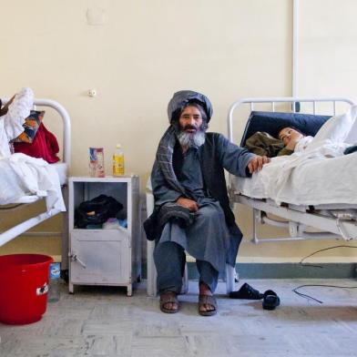 A father (middle) sits with his injured son in the male inpatient department of Boost hospital, Lashkargah, Helmand province. All services and high quality medicines are free of charge. MSF began supporting 155-bed Boost hospital with drugs, medical equipment, rehabilitation and on-the-job training for national staff in Nov 2009.