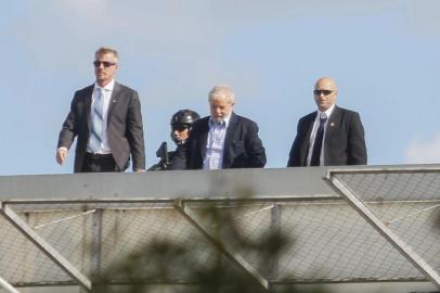 Brazilian former president Luiz Inacio Lula da Silva (C) is escorted as he arrives at the Federal Police headquarters in Curitiba, Parana state, Brazil where he is serving a 12-year prison sentence, after attending the funeral of his grandson in Sao Paulo, on March 2, 2019. - Lula, who is serving two concurrent 12-year sentences for corruption, was granted leave from prison to attend the funeral of his young grandson in Sao Paulo, who died at the age of seven. (Photo by Franklin De FREITAS / AFP)