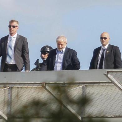 Brazilian former president Luiz Inacio Lula da Silva (C) is escorted as he arrives at the Federal Police headquarters in Curitiba, Parana state, Brazil where he is serving a 12-year prison sentence, after attending the funeral of his grandson in Sao Paulo, on March 2, 2019. - Lula, who is serving two concurrent 12-year sentences for corruption, was granted leave from prison to attend the funeral of his young grandson in Sao Paulo, who died at the age of seven. (Photo by Franklin De FREITAS / AFP)