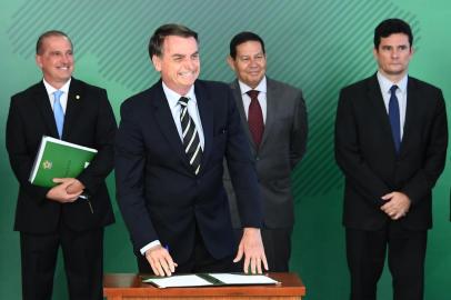  Brazilian President Jair Bolsonaro (2-L), accompanied by Chief of Staff Onyx Lorenzoni (L), Vice-President Hamilton Mourao (2-R) and Justice Minister Sergio Moro, smiles as he signs a presidential decree that flexibilizes the possession of firearms, at Planalto Palace in Brasilia, on January 15, 2019. - Bolsonaro decreed the easing of Brazils gun laws as part of a law-and-order agenda, despite fears it could aggravate already staggering violent crime. Brazil recorded nearly 64,000 homicides in 2017, making it one of the most dangerous countries in the world outside of a war zone. (Photo by EVARISTO SA / AFP)Editoria: POLLocal: BrasíliaIndexador: EVARISTO SASecao: governmentFonte: AFPFotógrafo: STF