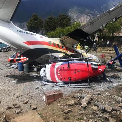  A Summit Air Let L-410 Turbolet aircraft bound for Kathmandu is seen after it hit two helicopters during take off at Lukla airport, the main gateway to the Everest region. - A small plane veered off the runway and hit two helicopters while taking off near Mount Everest on April 14, killing three people and injuring three, officials said. (Photo by STR / AFP)Editoria: DISLocal: EverestIndexador: STRSecao: accident (general)Fonte: AFPFotógrafo: STR