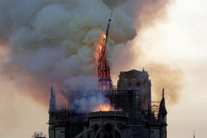  The steeple of the landmark Notre-Dame Cathedral collapses as the cathedral is engulfed in flames in central Paris on April 15, 2019. - A huge fire swept through the roof of the famed Notre-Dame Cathedral in central Paris on April 15, 2019, sending flames and huge clouds of grey smoke billowing into the sky. The flames and smoke plumed from the spire and roof of the gothic cathedral, visited by millions of people a year. A spokesman for the cathedral told AFP that the wooden structure supporting the roof was being gutted by the blaze. (Photo by Geoffroy VAN DER HASSELT / AFP)Editoria: DISLocal: ParisIndexador: GEOFFROY VAN DER HASSELTSecao: fireFonte: AFPFotógrafo: STR