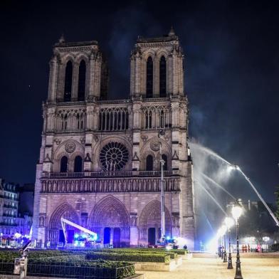  Firefighters gather at the facade of the Notre-Dame de Paris Cathedral as flames engulf the roof of the cathedral on April 15, 2019, in the French capital Paris. - A huge fire swept through the roof of the famed Notre-Dame Cathedral in central Paris on April 15, 2019, sending flames and huge clouds of grey smoke billowing into the sky. The flames and smoke plumed from the spire and roof of the gothic cathedral, visited by millions of people a year. A spokesman for the cathedral told AFP that the wooden structure supporting the roof was being gutted by the blaze. (Photo by STEPHANE DE SAKUTIN / AFP)Editoria: DISLocal: ParisIndexador: STEPHANE DE SAKUTINSecao: fireFonte: AFPFotógrafo: STF