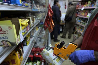 A customer pays in a small market in Buenos Aires on April 16, 2019, day in which the official statistics agency will announce the inflation rate of March. - President Mauricio Macri will announce on April 17 anti-inflationary measures to reactivate the economy in recession-hit Argentina. (Photo by Juan MABROMATA / AFP)