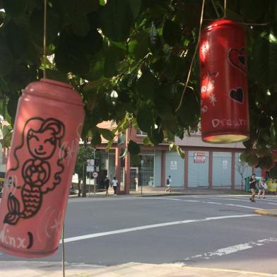 Alunos do Studio Santa Lata pintam latas das sobras de grafite, escrevem manifesto poético e as penduram em árvores no cntro de Caxias do Sul, na rua Maruês do Herval e Praça Dante. É o projeto Latas Poéticas.