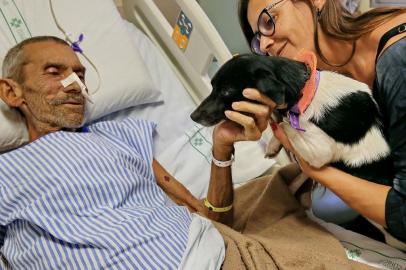 PORTO ALEGRE, RS, BRASIL,22/04/2019- Paciente Rossvelt Medeiros Laguna recebe a visita da cadela de estimação, Sol, trazida nos braços da filha, Leonice da Costa Laguna. Encontro aconteceu no Núcleo de Cuidados Paliativos do Hospital de Clínicas de Porto Alegre, na Unidade Álvaro Alvim. (FOTOGRAFO: JÚLIO CORDEIRO / AGENCIA RBS)