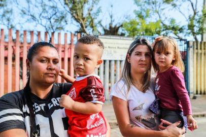  PORTO ALEGRE, RS, BRASIL, 17/04/2019: Mães com filhos que estão na fila por vaga em creche.  Gilviane Gawlinki, com a filha Maria Eduarda e Scheila Salgado com o filho Cristian  em frente à Emei Vila Nova Restinga. (Foto: Omar Freitas / Agência RBS)