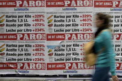 A woman walks past banners placed by the Argentinian bank workers union showing how much food prices have increased since the beginning of the government of Argentinas President Mauricio Macri and calling a strike for next April 30 at the financial district in Buenos Aires, on April 25, 2019. - Since his election in 2015, the market-friendly former Buenos Aires mayor has launched important economic reforms to balance years of spending by the previous leftist government of Cristina Kirchner -- but his promises to defeat inflation and place Argentina on the path to sustained growth have proved empty. (Photo by JUAN MABROMATA / AFP)