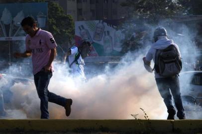  Venezuelans run away from tear gas during scuffles with security forces in Caracas on April 30, 2019. - Venezuelan opposition leader and self-proclaimed acting president  Juan Guaido said on Tuesday that troops had joined his campaign to oust President Nicolas Maduro as the government vowed to put down what it said was an attempted coup. (Photo by Yuri CORTEZ / AFP)Editoria: WARLocal: CaracasIndexador: YURI CORTEZSecao: crisisFonte: AFPFotógrafo: STF