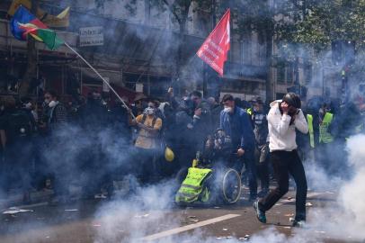 Protesters wearing protective masks gather while tear gas smke billows around them  prior to the start of the annual May Day rally in Paris on May 1, 2019. - France's zero-tolerance approach to protest violence will be tested on May 1, when a heady mix of labour unionists, "yellow vest" demonstrators and hardline hooligans are expected to hit the streets on Labour Day. (Photo by Anne-Christine POUJOULAT / AFP)