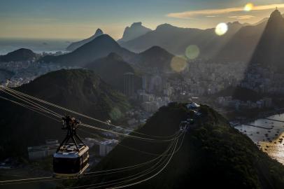 Cable cars climb Sugarloaf Mountain as the sun sets in Rio de Janeiro. RIO DE JANEIRO, Brazil â BC-TRAVEL-TIMES-36-RIO-ART-NYTSF â Cable cars climb Sugarloaf Mountain as the sun sets in Rio de Janeiro. To come to this sprawling, dynamic Brazilian city without preconceptions, whether theyâre about bikinis or President Jair Bolsonaro, is just about impossible. But Rio constantly finds ways to surprise â whether itâs a friendly resident walking you to a shop you just canât find; sobering evidence of the cityâs slave trade; or the discovery that food tastes best standing on a sidewalk surrounded by the lyrical sound of Portuguese and accompanied by a beer so cold itâll make your fillings hurt. (CREDIT: Dado Galdieri/The New York Times)--ONLY FOR USE WITH ARTICLE SLUGGED -- BC-TRAVEL-TIMES-36-RIO-ART-NYTSF -- OTHER USE PROHIBITED.Editoria: TRALocal: Rio de JaneiroIndexador: Dado GaldieriFonte: NYTNSFotógrafo: STR