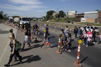 SAPUCAIA DO SUL, RS, BRASIL, 02-05-2019: Alunos da Escola Municipal Afonso Guerreiro Lima, em Sapucaia do Sul, se arriscam para atravessar a RS-118 depois da retirada da passarela que existia no local para obras na rodovia. Guardas municipais auxiliam com o trânsito em determinados horários. (Foto: Mateus Bruxel / Agência RBS)