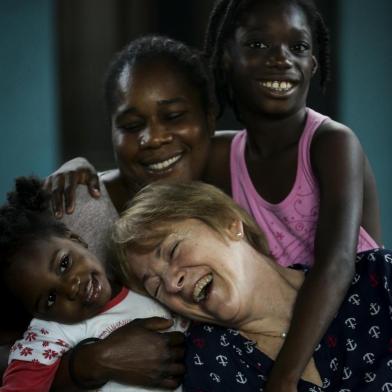 PORTO ALEGRE, RS, BRASIL, 28-04-2019: A técnica em enfermagem Neusa Scherer, 64 anos, durante visita à casa da haitiana Guerline Exume, com os filhos, Wildialine, 7, e os gêmeos Wisline (E) e Woosley, 2, na zona norte. Neusa criou o Grupo de Voluntários Família Imigrante, que auxilia os estrangeiros em Porto Alegre. Devido à dedicação e carinho dela com haitianos e senegaleses, eles a chamam de mãe. (Foto: Mateus Bruxel / Agência RBS)