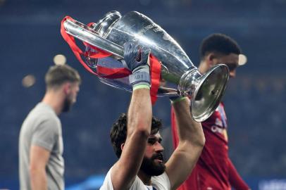 Liverpools Brazilian goalkeeper Alisson raises the European Champion Clubs Cup as he celebrates after winning the UEFA Champions League final football match between Liverpool and Tottenham Hotspur at the Wanda Metropolitano Stadium in Madrid on June 1, 2019. (Photo by Paul ELLIS / AFP)